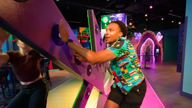 A guest playing a high-energy reaction game at Level 99 Disney Springs, hitting glowing buttons on a machine.