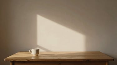 Warm side-lit empty creative studio, a wooden desk with a single ceramic cup, soft shadows on a plaster wall, minimalist 35mm photography