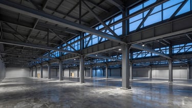 Interior of a massive modern logistics center with exposed steel trusses and polished concrete floor, sharp architectural lines, twilight light filtering through high windows