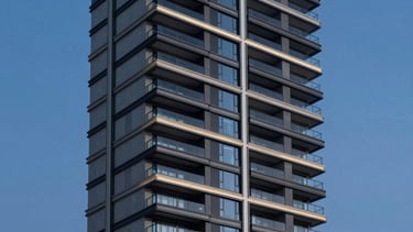 High-angle architectural shot of a luxury vertical residential tower, cantilevered concrete balconies, high-contrast twilight sky