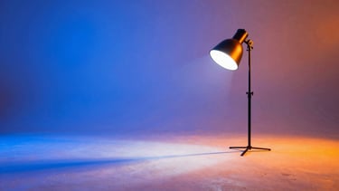 Vibrant studio photography of a high-contrast creative set, electric blue and orange gel lights casting sharp shadows on white concrete, 35mm.