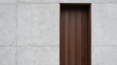 Straight-on architectural detail shot of custom dark oak joinery meeting a raw light-gray concrete wall, soft overcast daylight.