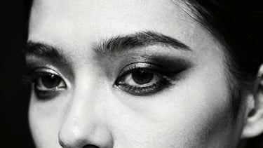 Backstage runway model, extreme close-up of eye makeup, sharp chiaroscuro lighting, deep blacks and pure whites, 35mm, high-contrast dramatic strobe lighting.