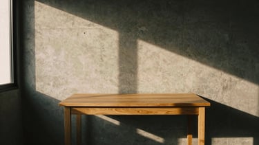A minimalist workspace in Hyderabad, a single raw oak desk against a textured concrete wall, long dramatic shadows from golden-hour light through a high window, 35mm film.