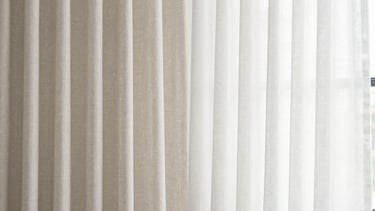 Before and after comparison of heavy linen curtains, left side dusty and grayed by pollution, right side bright white and crisp, natural window light, 35mm
