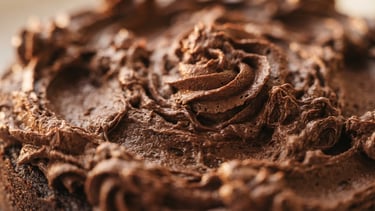 Macro shot of textured chocolate buttercream frosting under soft golden-hour window light, shallow depth of field, 35mm