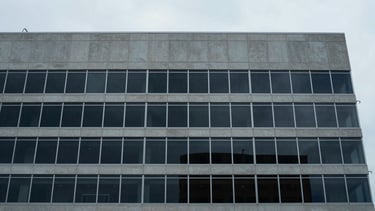 Wide-angle architectural perspective of a modern, minimalist office building facade in downtown Tampa, overcast morning light, muted desaturated blue and concrete tones, sharp focus, 35mm lens
