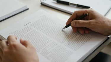 Close-up of hands turning pages of a printed research report, text in a non-English language visible, with a pen and notebook nearby, soft natural light, candid human interaction.