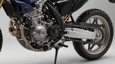 Close-up 45-degree shot of a motorcycle engine casing and chain drive assembly on a clean studio surface, oil filler cap and sprocket teeth in sharp focus, neutral studio key light from the left revealing metal texture and part markings