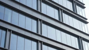 Close-up of clean architectural glass and steel surfaces in a modern corporate headquarters, bright natural daylight, cool blue and slate gray tones, sharp focus