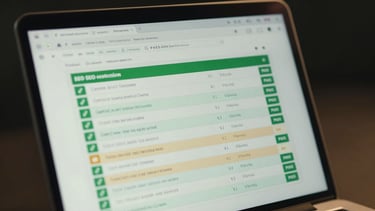 Focused close-up of a laptop screen showing a technical SEO audit report with green pass indicators and a few flagged items in amber, dark background behind the laptop, cool studio lighting creating a slight glow on the screen