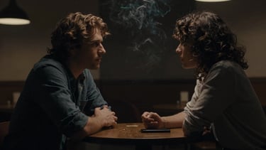 Cinematic film still, moody portrait of two people talking in a dimly lit cafe, soft smoke, rich shadows, 35mm anamorphic lens.