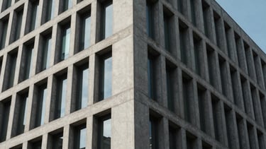 Sharp architectural angle of a modern concrete office building facade under crisp, cool daylight.