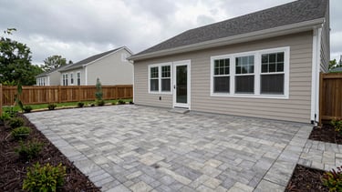 Wide environmental shot of a completed backyard patio in a DC-area residential property, overcast daylight, full paver or concrete deck visible with surrounding landscaping, no people, honest finished-result framing