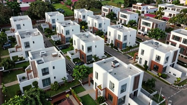 Wide panoramic drone shot of an organized premium villa community in Andhra Pradesh, modern white and terracotta structures surrounded by manicured green spaces.