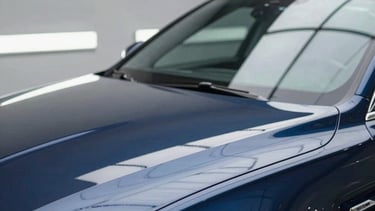 Professional car detailing setting in North American / US, shining clean car surface reflecting light, modern garage, colors like dark blue and light gray, elegant, high quality photography.
