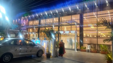 Illuminated luxury wedding convention hall exterior with blue LED lights and floral decorations.