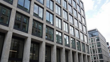 Wide architectural elevation shot of a modern concrete and glass office building in London, crisp morning light, sharp focus, 35mm lens.