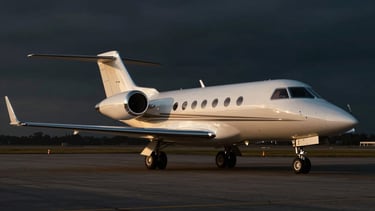 Cinematic wide shot of a private jet landing on an airport tarmac at golden hour, warm reflections on polished chrome, deep rich blacks, 35mm anamorphic lens.