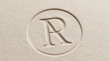 Macro photography of a minimalist logo embossed on high-quality cream-colored cardstock, soft shadow, elegant South American / Brazilian design aesthetic.