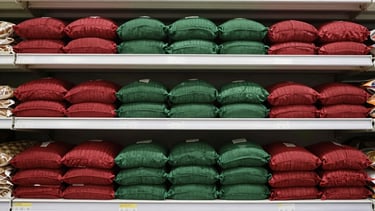Straight-on eye-level shot of neatly aligned grocery shelves stocked with bulk dry goods under bright clean commercial store lighting