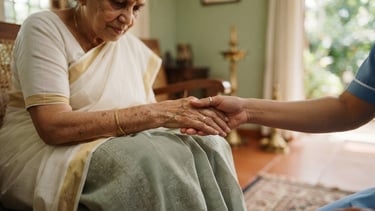 Close-up of a professional caregiver's hands gently holding an elderly patient's hand in a warm, sunlit Kerala home, soft focus, serene atmosphere.