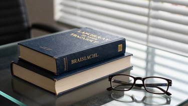 Still life of architectural legal books and a pair of spectacles on a glass table. Morning light filtering through blinds, creating a sophisticated and intellectual mood in a Brazilian office.