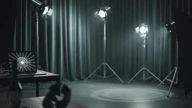 Professional studio setup with photography spotlights, curtains, and a laptop displaying graphic art.