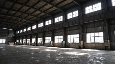 Wide angle industrial facility interior, high-contrast natural factory light, deep slate and amber tones, 35mm