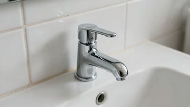 Close-up overhead shot of freshly cleaned white ceramic tiles and polished chrome tap in a bathroom, natural north-facing light, no people, sharp detail on grout lines and dry surface
