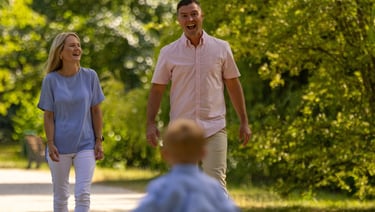 Familienshooting Coburg: Fröhlicher Sohn rennt lachend auf seine Eltern zu, pure Lebensfreude.