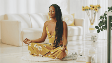 a woman sitting on a rug in a living room meditating