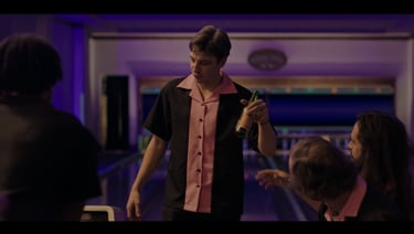a man in a bowling shirt is holding a bottle of beer