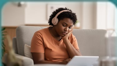 A person sitting comfortably, appearing to be in a calm, reflective state within an indoor setting.