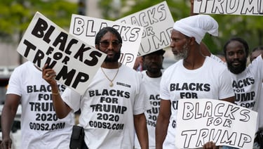 Black Americans holding signs that say "blacks for Trump"