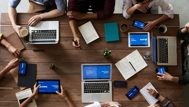 a group of people sitting around a table with laptops