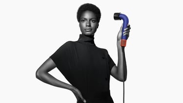 A model with short natural hair holding a professional Dyson Supersonic r hair dryer.