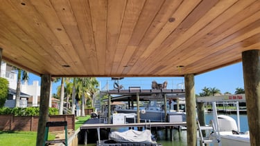 Custom tongue and groove ceiling installation on a boat dock overlooking a canal with luxury yachts.