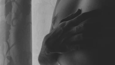 Mano sobre el pecho en primer plano con luz suave lateral.