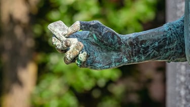 Close-up of Steve Jobs statue’s hand holding the first iPhone, symbolizing innovation.