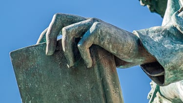 Close-up of János Arany’s hand resting on a book, symbolizing literary legacy.
