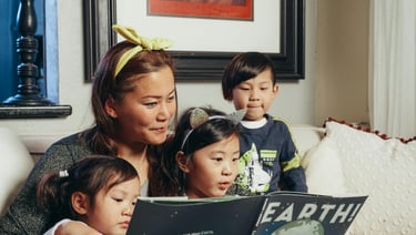 a woman and three children reading a book