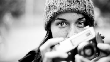 Student in fine art photography courses holding a vintage camera, black and white portrait.