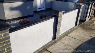 Blue perfurated brick wall with black coping and caps and grey rendering