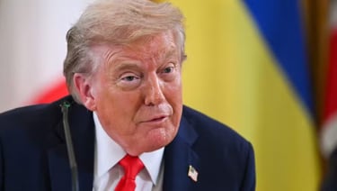 Close de Donald Trump com gravata vermelha, falando em uma mesa.