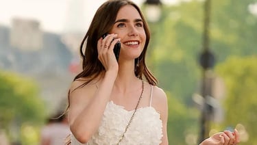 Lily Collins sorrindo e falando ao telefone, vestida de branco em Paris.