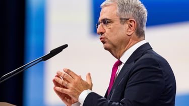 a man in a suit and tie is speaking into a microphone