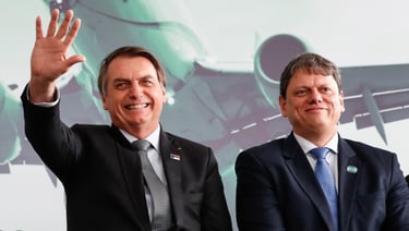 two men in suits and ties standing in front of a large screen