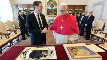 a man in a red robe shaking hands with a priest