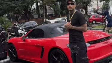 a man in a black shirt and sunglasses standing next to a red sports car